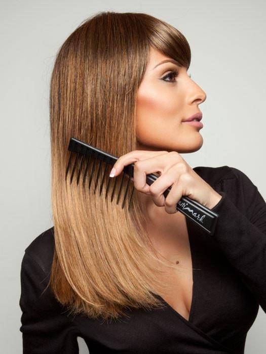 Model using Beautimark wide toothed comb to brush a brunette wig that she is wearing. 