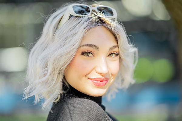 Woman smiling while wearing a Mid-Length wig. 